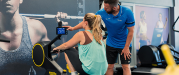 York sport customer using rowing machine assisted by staff member